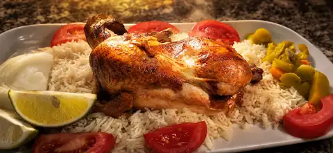 دجاجة كاملة على صحن رز مع طماطة وليمون